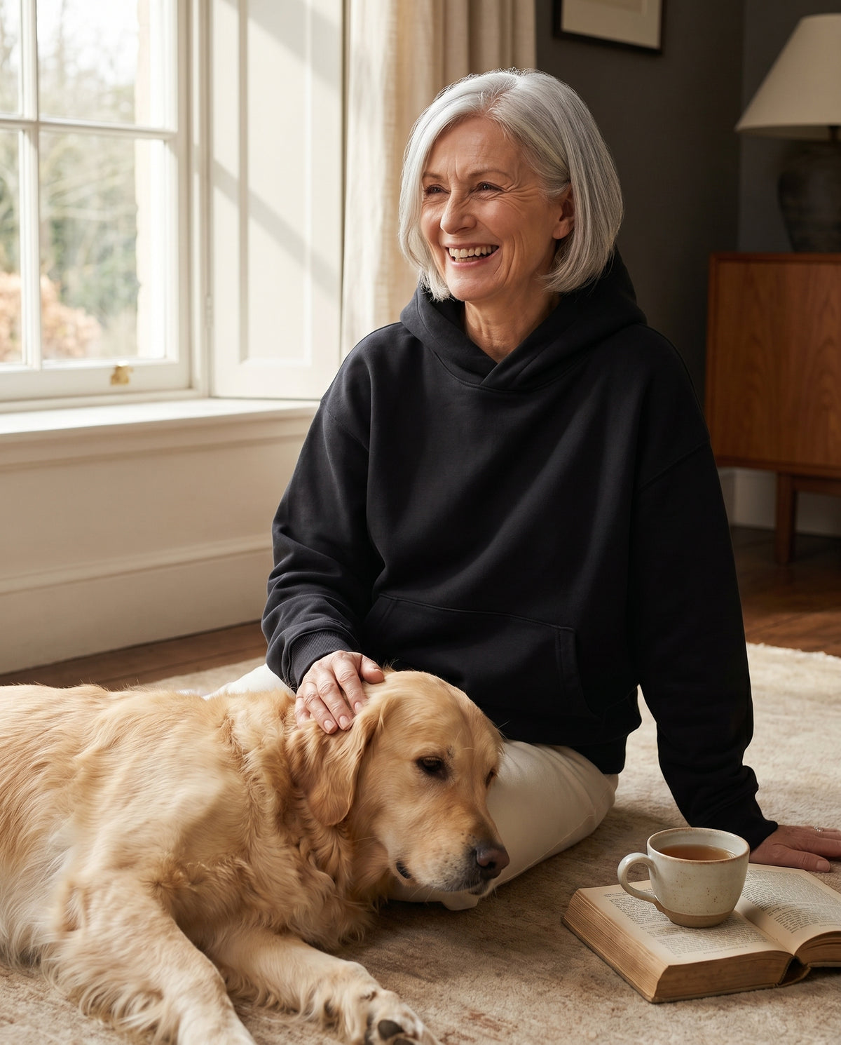 A 60-year-old woman sitting with her dog wearing the Sensory Hoodie